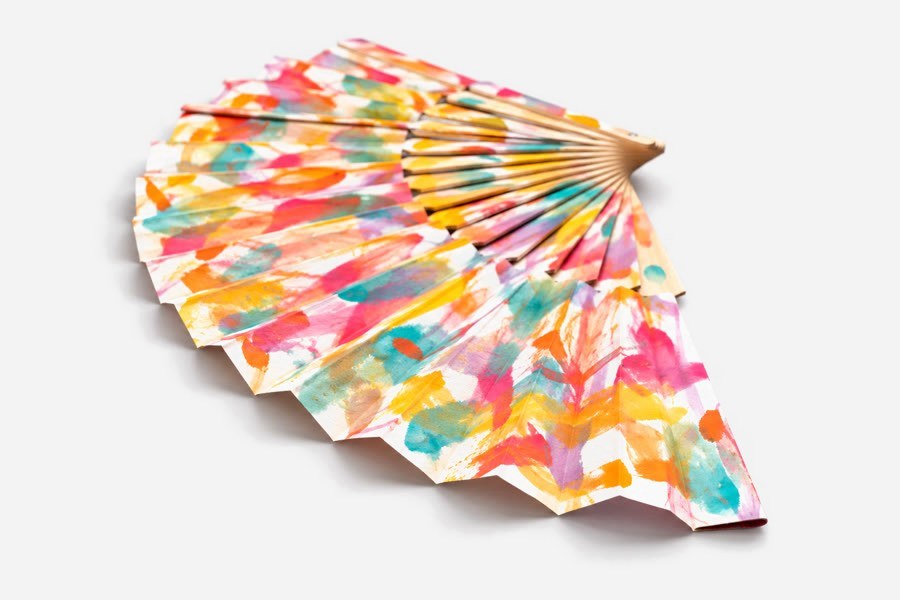 Leque de madeira e papel pintado com manchas de cor rosa, laranja, amarelo e turquesa